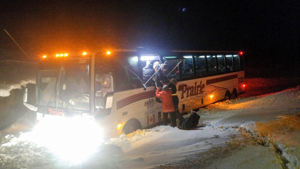 A bus lies ditched in snow outside Yellowknife as Arctic Winter Games athletes exit through the emergency escape - Sarah Pruys