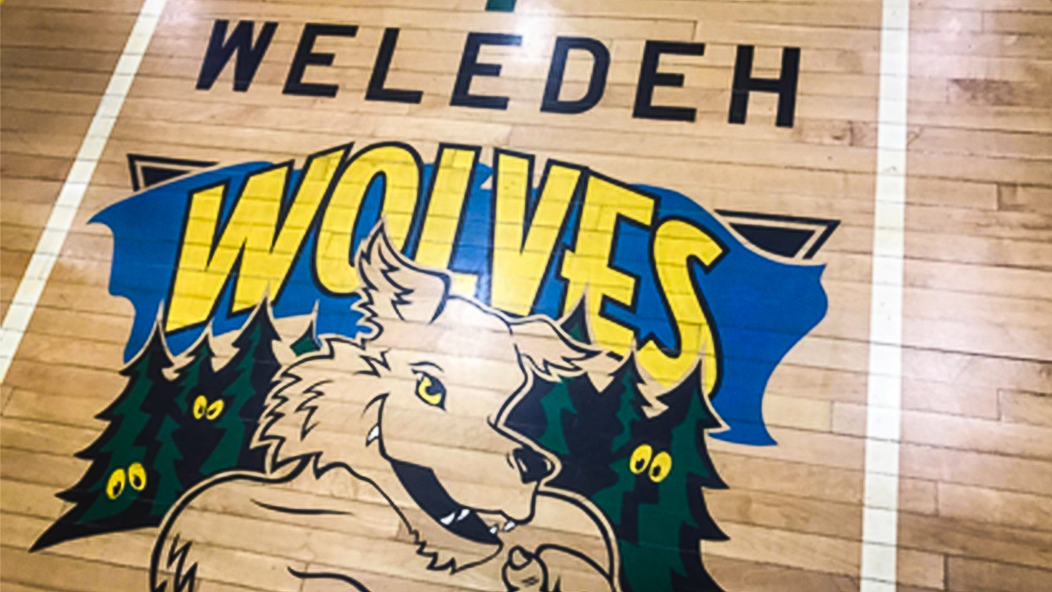 An image of the Weledeh Wolves logo on the school's gym floor, included in a presentation advocating for the school's name to change
