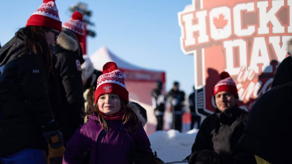 A child poses in front of the Hockey Day in Canada sign during the hockey festival in Yellowknife. Sarah Pruys/Cabin Radio