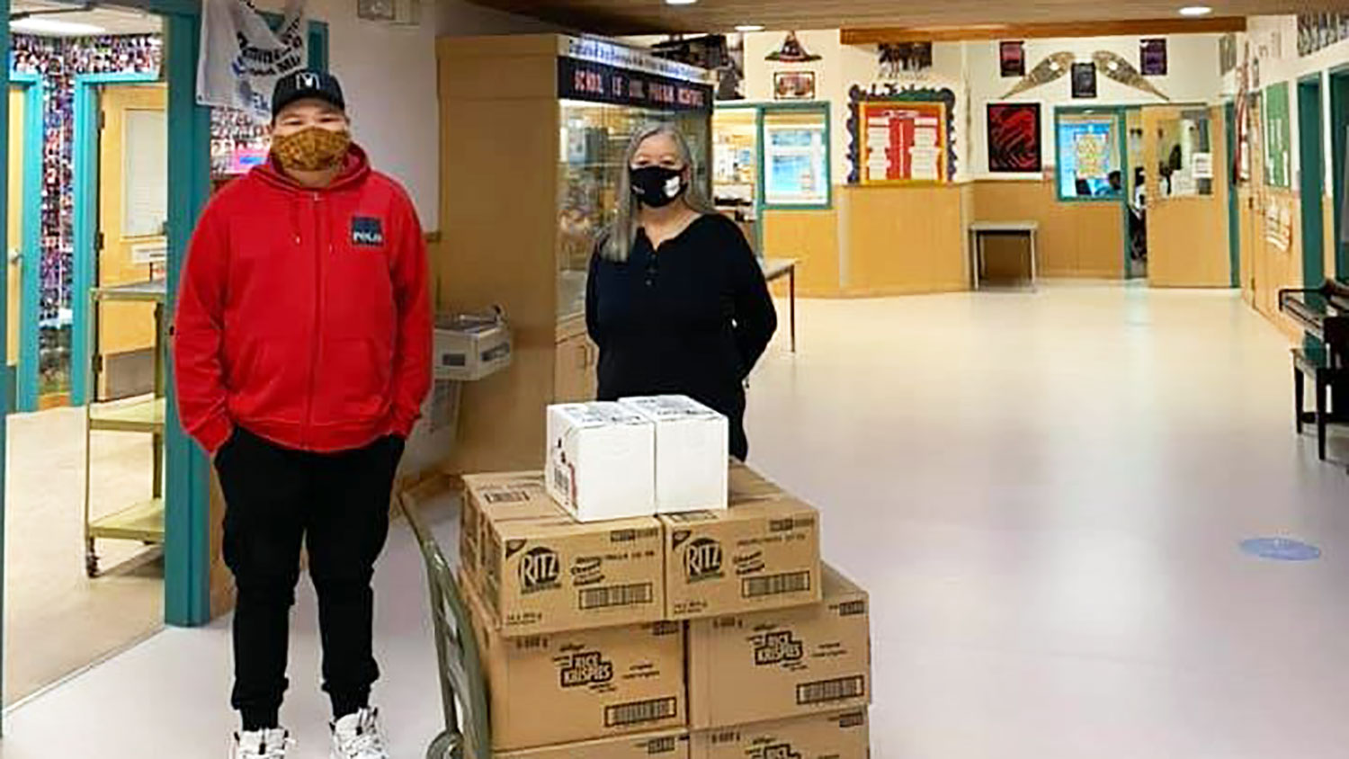 Marlin Miersch-King, 13, stands next to Principal Lynette De Maries and a shipment of snacks for his classmates