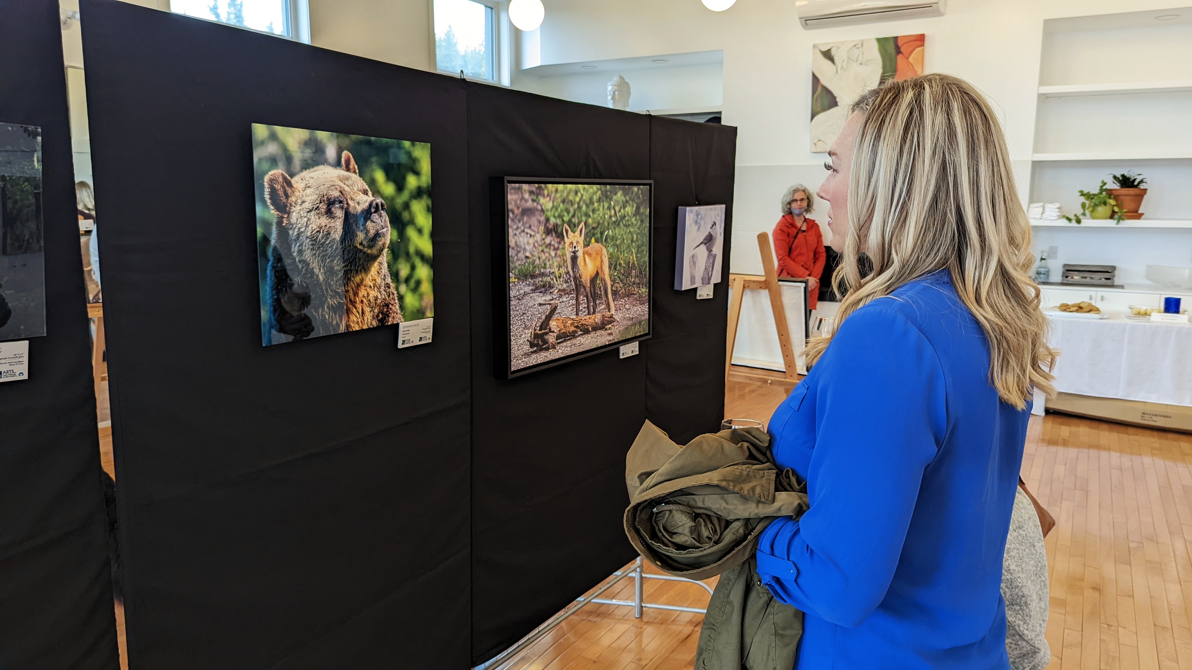 An art show visitor meets Sunshine Bear, a Wiley Wolfe photo, at Yellowknife's Racquet Club