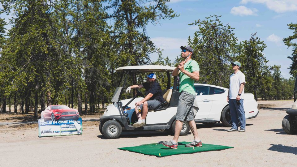 Joey Borkovic swings, but doesn't manage to get the hole-in-one that would win him a Mustang. Sarah Pruys/Cabin Radio
