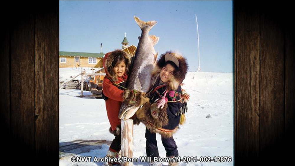 Celine Ritias and John Blancho Jr hold up a frozen fish in Colville Lake in 1977. Bern Will Brown/NWT Archives