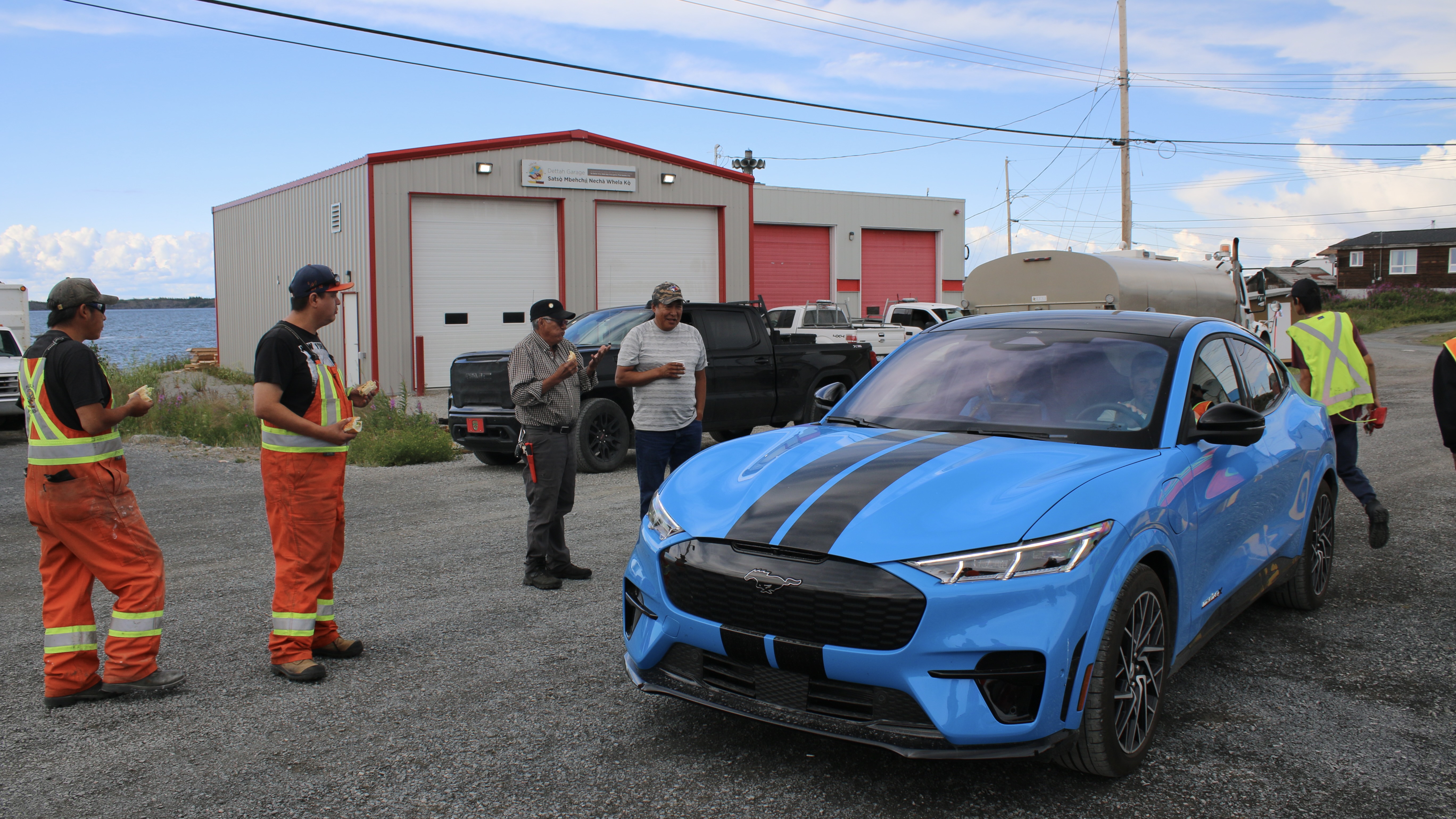 A small crowd gathers around a new electric sports car at an EV information session hosted by the Yellowknives Dene First Nation