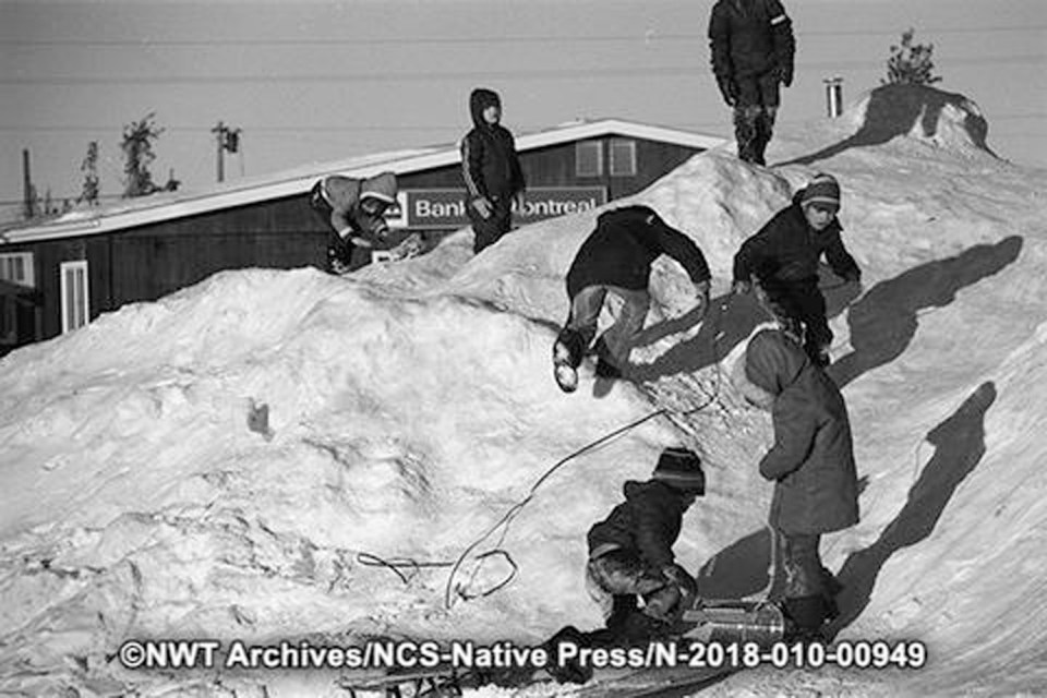 Children play on a snow pile in Hay River in January 1973