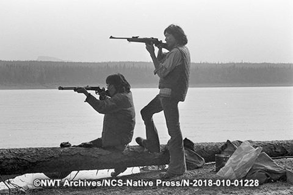 Men with rifles by the Mackenzie River in Fort Good Hope on July 18, 1973