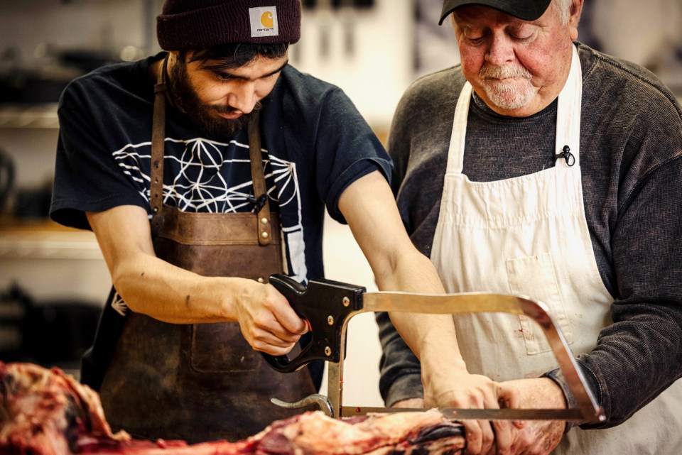 Jaryd McDonald uses a saw to cut through a piece of muskox, while Duane Bohlken holds it still. Josh Ferguson/Norteno Media