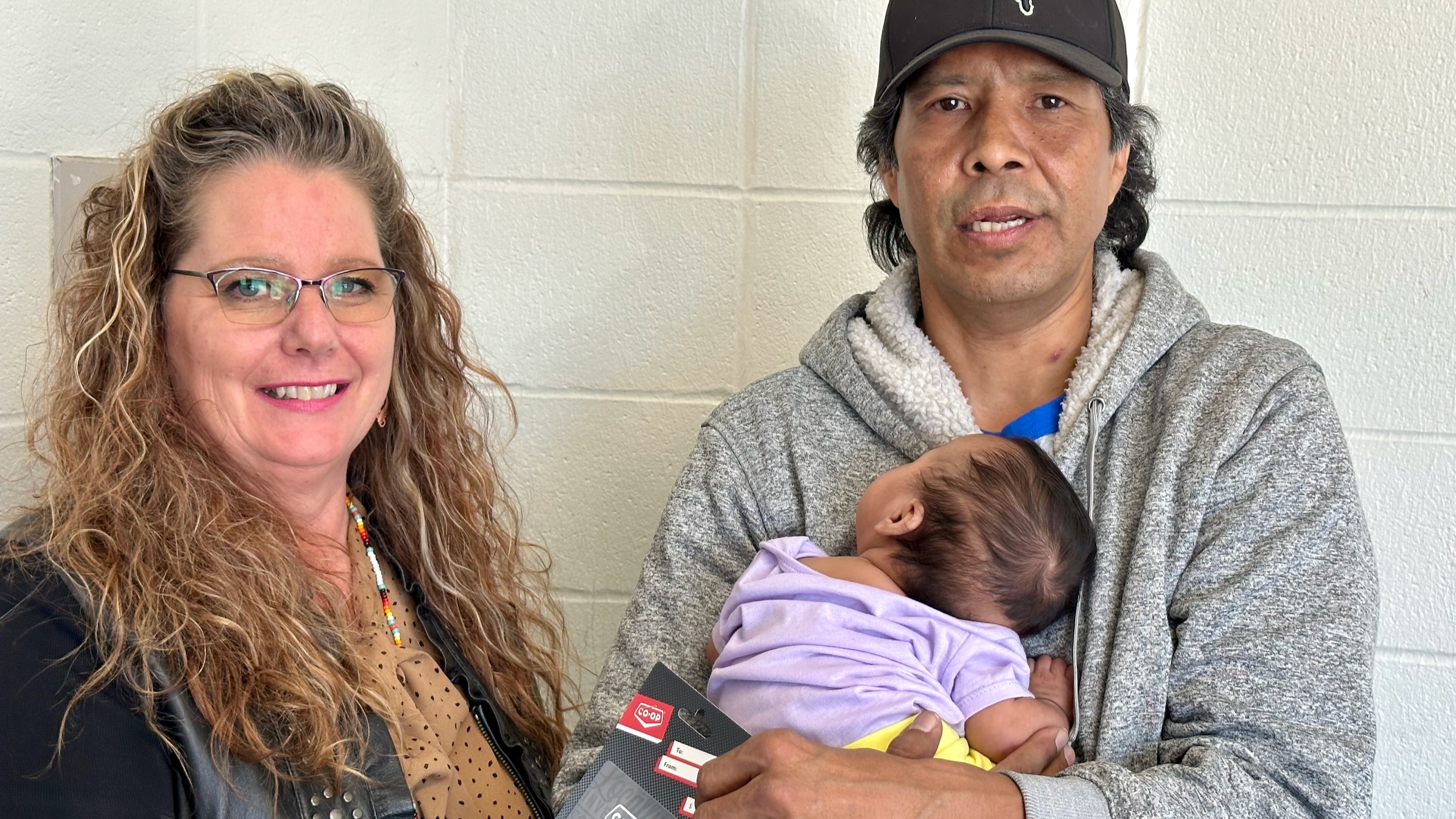 Lorie-Anne Danielson hands a gift card supplied by United Way NWT to Arnold Sabourin and baby Tiffany after May 2023's wildfires. Photo supplied by David Connelly
