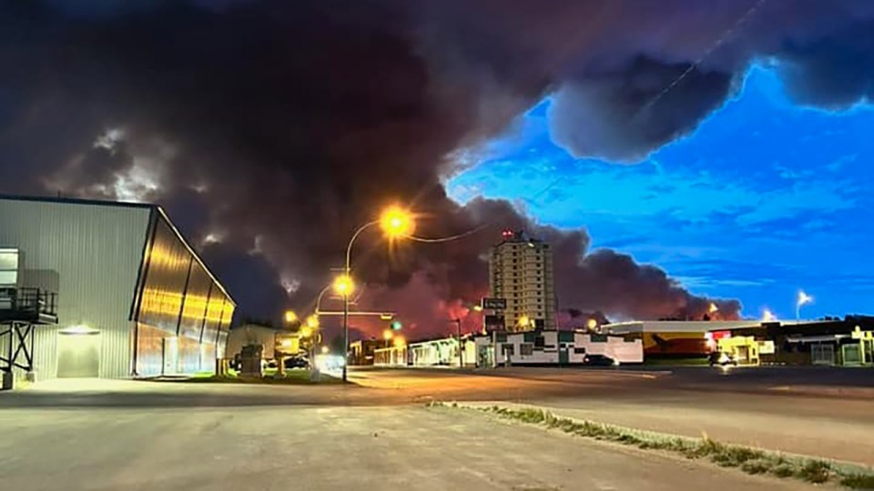 A wildfire's smoke plume looms over Hay River on the evening of May 14, 2023