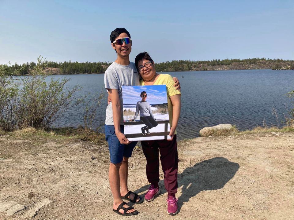 Frank Gruben's mother and brother hold a photo of him in an image uploaded to Facebook last month
