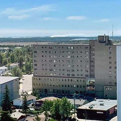 In the distance, a grey, near-horizontal plume of wildfire smoke can be seen from downtown Yellowknife in a photo published by the GNWT.