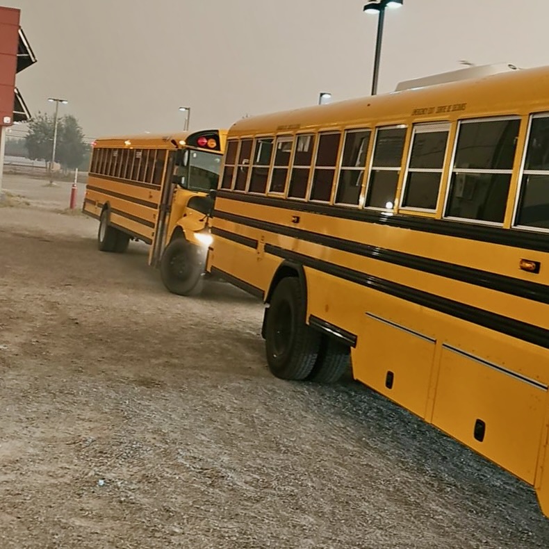 Buses wait to take remaining Behchokǫ̀ residents to flights on July 25, 2023. Photo: Pushp Seth