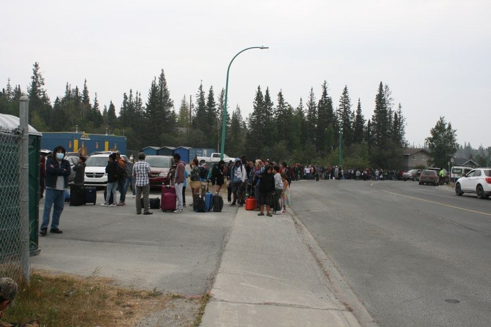 Yellowknife residents line-up at a high school downtown to catch at shuttle to the airport for an evacuation flight. Emma Stuart-Kiss/Cabin Radio