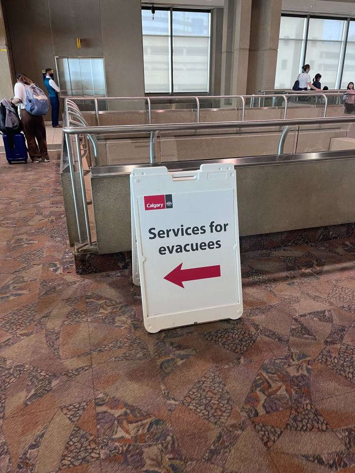 A board directs evacuees toward extra supports at Calgary Airport. Aastha Sethi/Cabin Radio