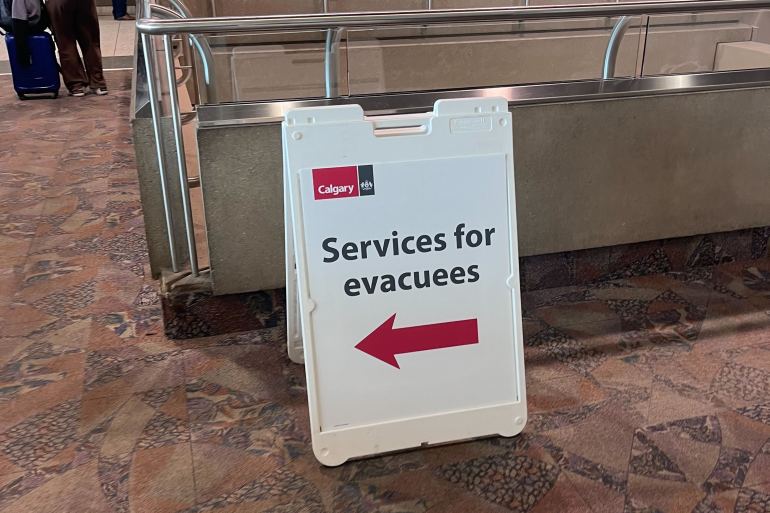 A board directs evacuees toward extra supports at Calgary Airport. Aastha Sethi/Cabin Radio