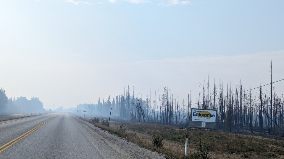 The "Welcome to Enterprise" sign still stands amid burnt trees. Sarah Pruys/Cabin Radio