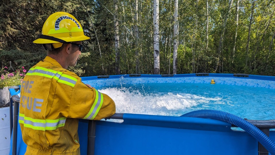 A firefighter in Hay River uses a pool to assist with firefighting efforts. Photo: Town of Hay River