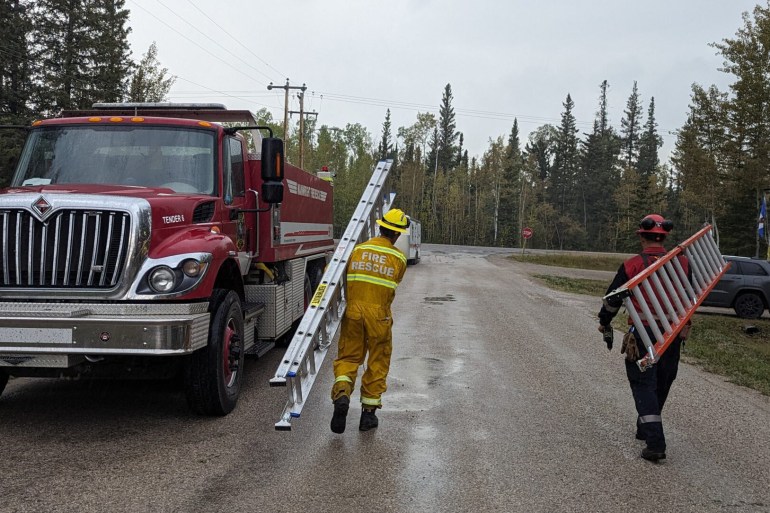 Firefighters in Hay River carry ladders down a road. Photo: Town of Hay River
