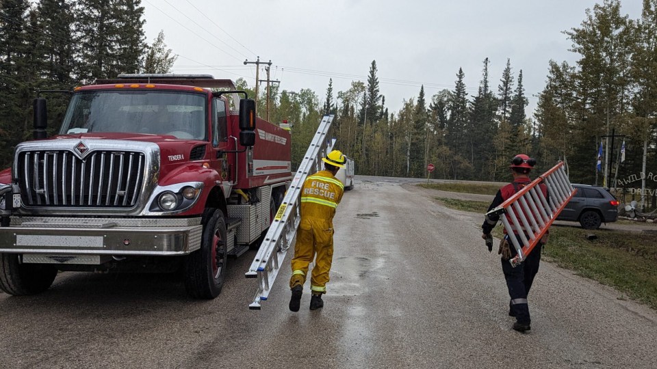 Firefighters in Hay River carry ladders down a road. Photo: Town of Hay River