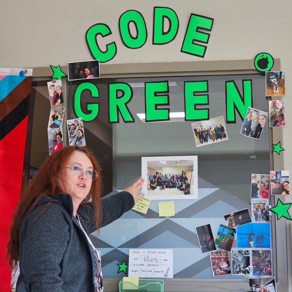 Jennifer Torode at a wall of photos and memorabilia from Stanton's August Code Green. Ollie Williams/Cabin Radio