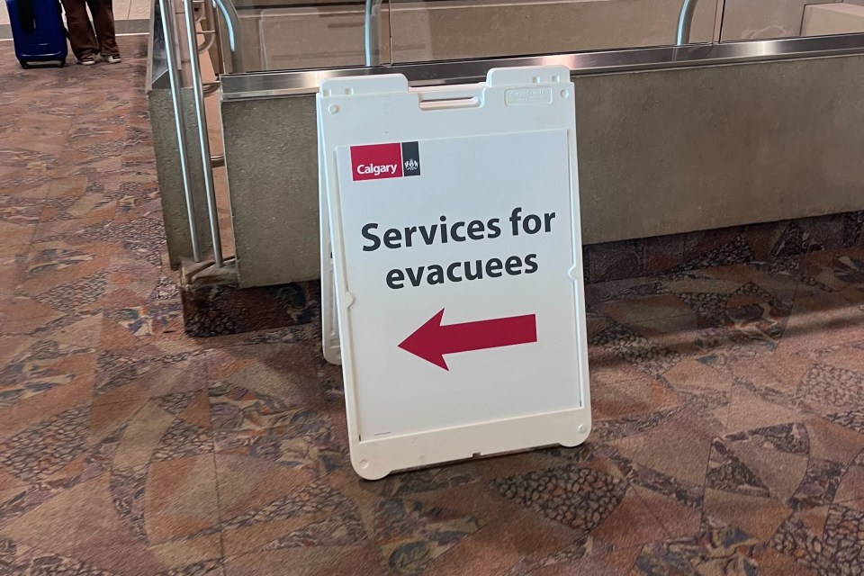 A board directs evacuees toward extra supports at Calgary Airport. Aastha Sethi/Cabin Radio