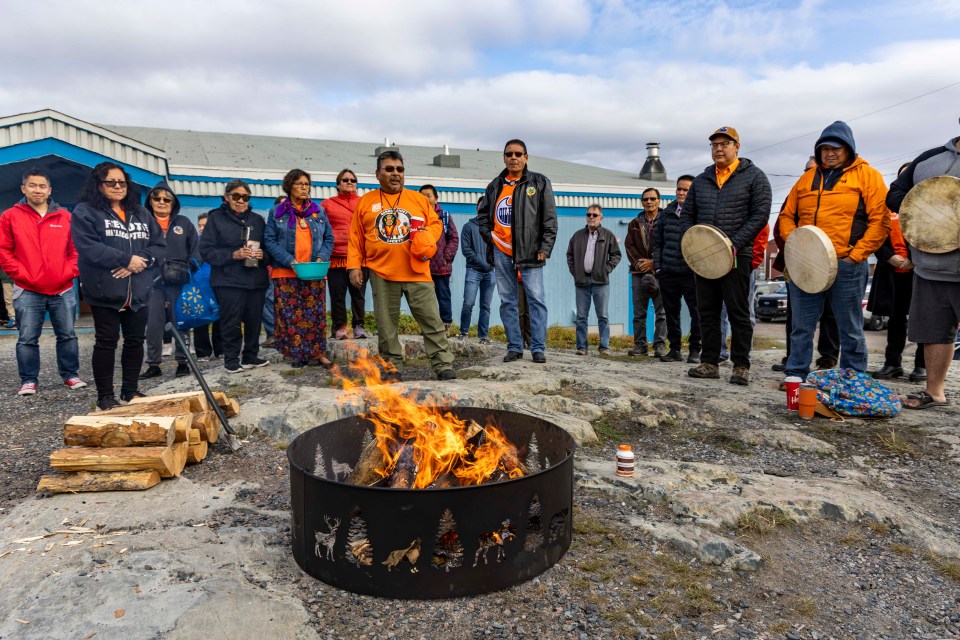 The beginning of a feeding-the-fire ceremony outside the Ndılǫ gym on September 30, 2023.