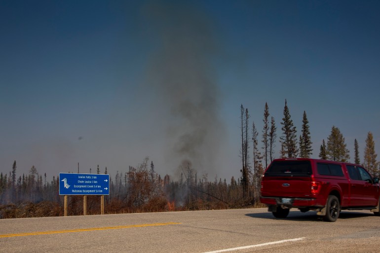 Traffic passes a small spot fire in a slash pile metres from Highway 1 near Alexandra Falls on September 15, 2023. Photo: Bill Braden