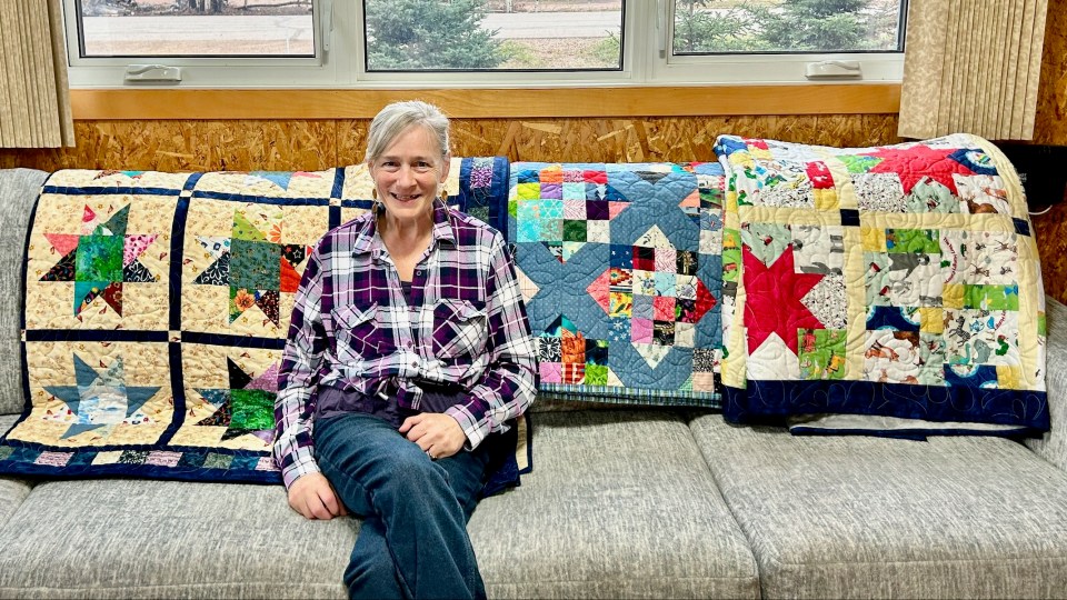 Sandra McMaster poses with homemade quilts she plans to donate to Enterprise residents who lost their homes in this season's wildfires. Photo: Craig McMaster