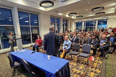 MLAs-elect Kate Reid (front row, red) and Julian Morse (second row, checked shirt) listen to a presentation from Diavik diamond mine's Angela Bigg at the 2023 Yellowknife Geoscience Forum. Ollie Williams/Cabin Radio