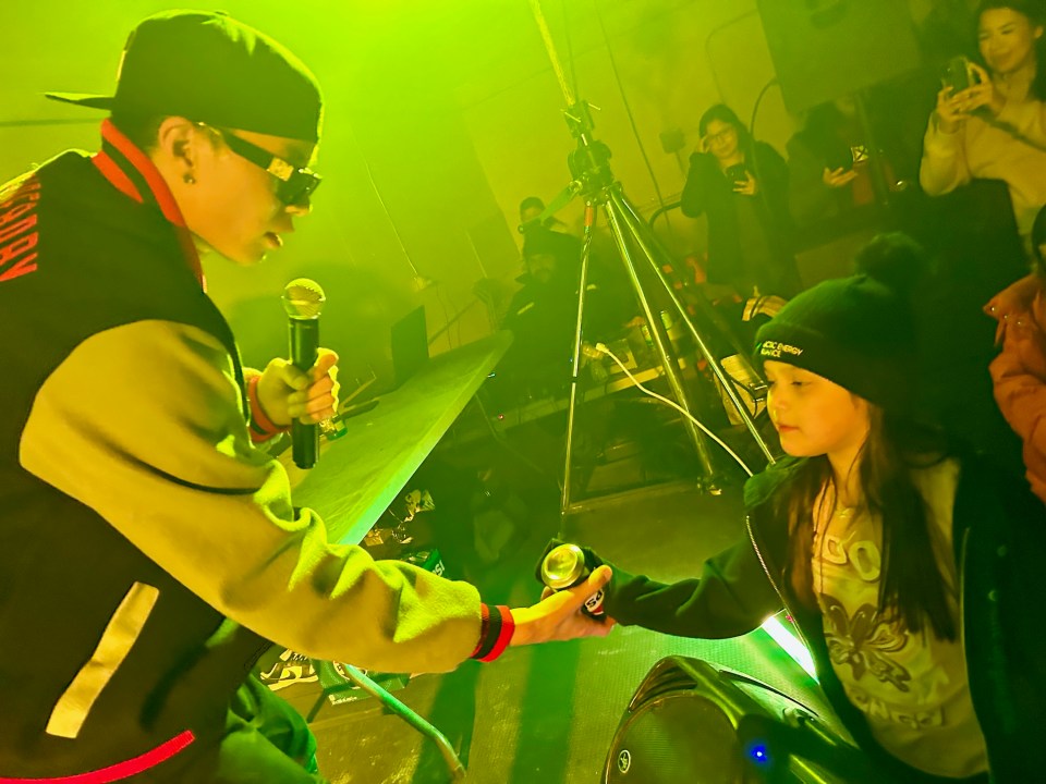 NorthSideBaby hands signed pop cans to audience members. Kaylee Nitsiza for Cabin Radio