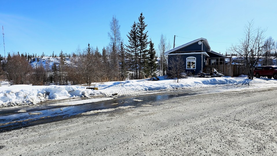 Spring meltwater runs along the side of Rycon Drive where heating oil had spilled the night before. Ollie Williams/Cabin Radio
