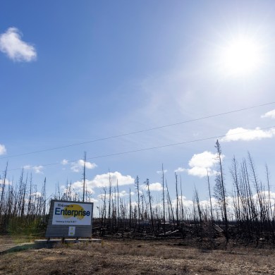 A welcome sign for the hamlet of Enterprise next to a burn area in April 2024. Ollie Williams/Cabin Radio