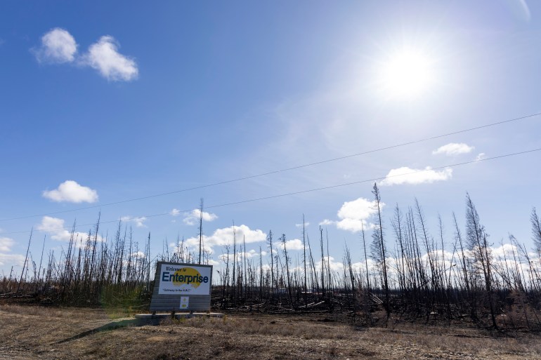 A welcome sign for the hamlet of Enterprise next to a burn area in April 2024. Ollie Williams/Cabin Radio