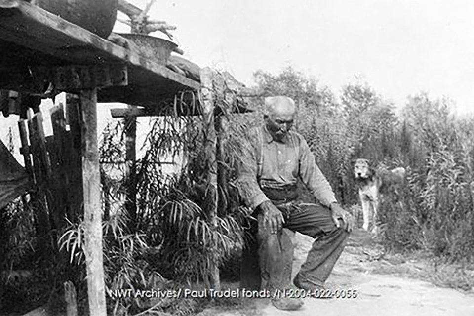 A photo taken by Paul Trudel in 1928 shows Alexander Kennedy, by then known as "Old Alex" Kennedy, with his dog outside his cabin in the vicinity of Fort Smith. NWT Archives/Paul Trudel fonds/N-2004-022: 0055