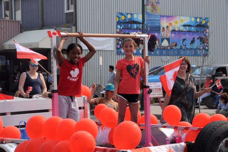 Two young participants ride in a parade float during Yellowknife's Canada Day 2024 celebration. Caelan Beard/Cabin Radio