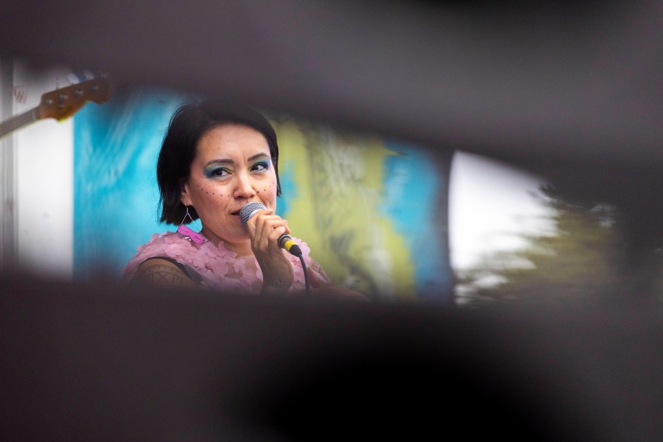 Beatrice Deer appears between a gap in the speaker stack at the Beer Garden Stage. Ollie Williams/Cabin Radio