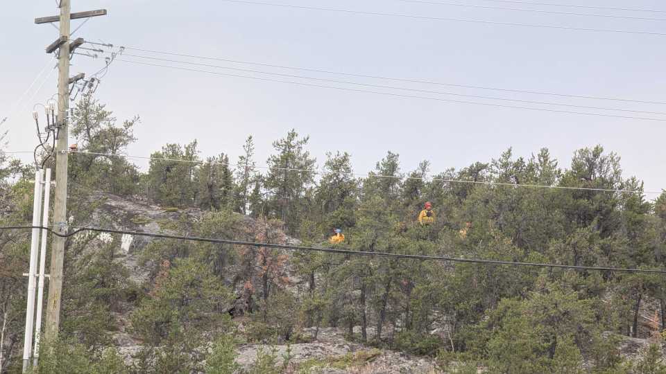 Fire crew members are seen in an area of land near the NWT legislature. Sarah Pruys/Cabin Radio