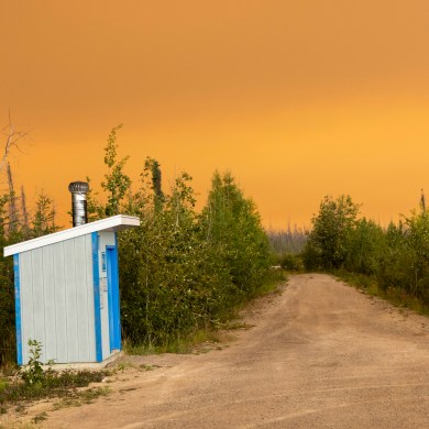 A washroom at a roadside pullout on Highway 3 as smoke from a wildfire covers the sky overhead on August 9, 2024. Ollie Williams/CabinRadio