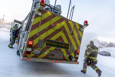 A firefighter races to an engine as a Yellowknife fire crew responds to a call on January 9, 2025. Ollie Williams/Cabin Radio