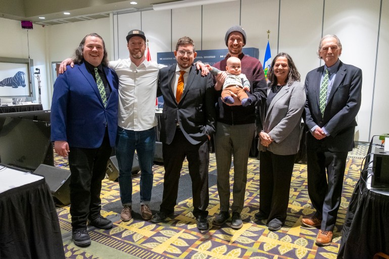 From left: Cabin Radio's Jesse Wheeler, Andrew Goodwin, Ollie Williams and Scott Letkeman (with son Porter) alongside consultants Rita Cugini and Andrew Forsyth at a hearing for an FM licence on February 11, 2025. Photo: Bill Braden