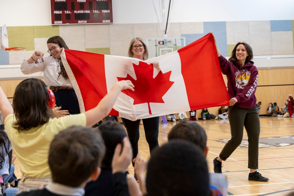École Allain St-Cyr's Gwenan Guillas-Letain, Ingrid Wood and Lisandre St-Amant parade with the Canadian flag. Ollie Williams/Cabin Radio