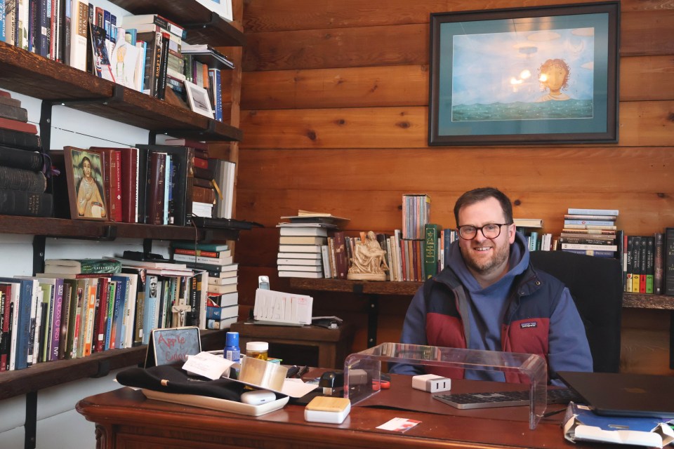 Reverend Francis Delaplain sits in his office at St Andrew’s Anglican Church among pieces of religious art and a small collection of fantasy novels. Claire McFarlane/Cabin Radio