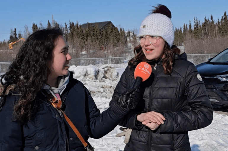 Jasmine Nasogaluak interviews a tea-boiling contender at the 2025 YKDFN Spring Carnival. Ehxea Antoine/Cabin Radio
