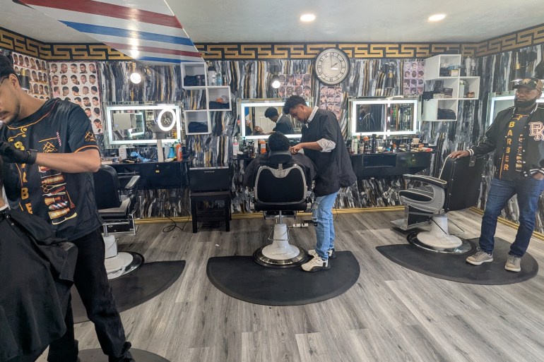 Three men in a barbershop cutting hair