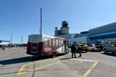 A hotel shuttle bus waits outside Yellowknife Airport in June 2025. Ollie Williams/Cabin Radio