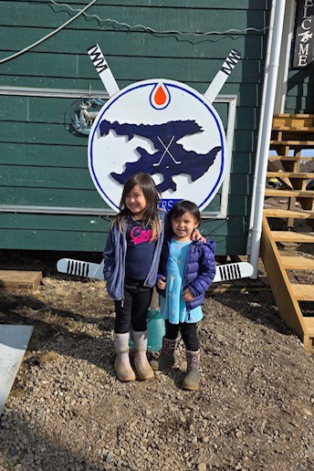 Girls stand in front of an Great Bear Lake Oilers sign made by Greg Kenny. Photo: Elaine N Kenny