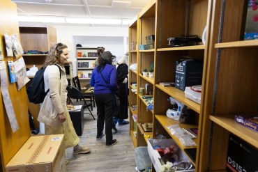 People browse shelves of the Next to New thrift store during a tour on June 20, 2025. Ollie Williams/Cabin Radio