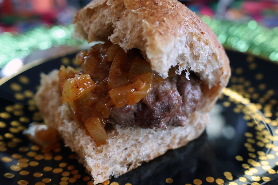 Close-up of a slider on a bun topped with sauce