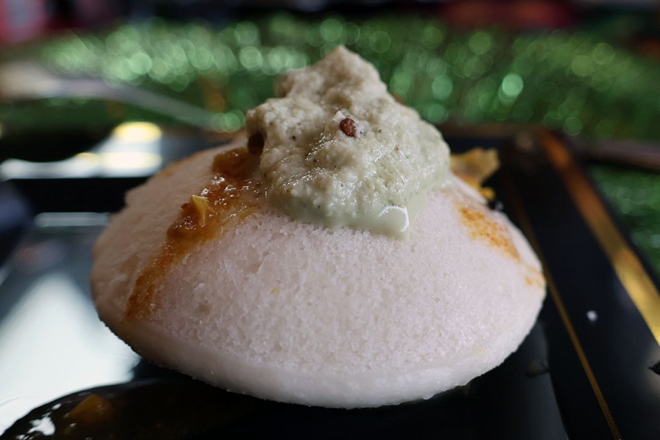 close-up of a fluffy rice cake topped with a green savoury sauce