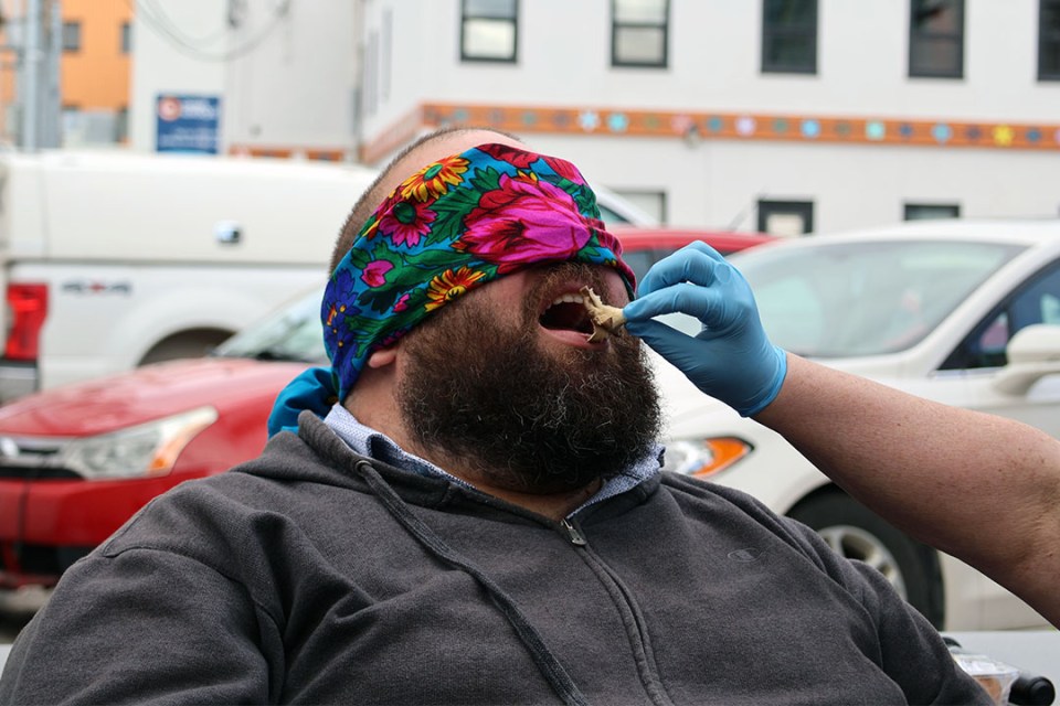 A man is blindfolded and a mushroom is placed in his mouth for a taste test.